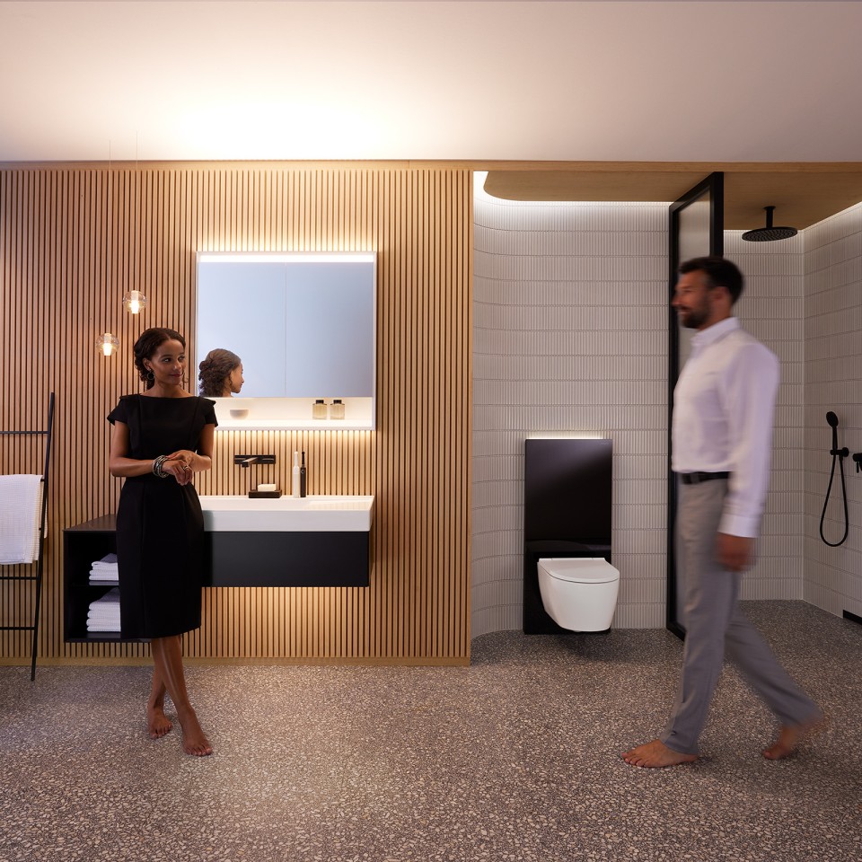 Man and woman in perfectly lit bathroom with Geberit ONE bathroom furniture and ceramic appliances (© Geberit)