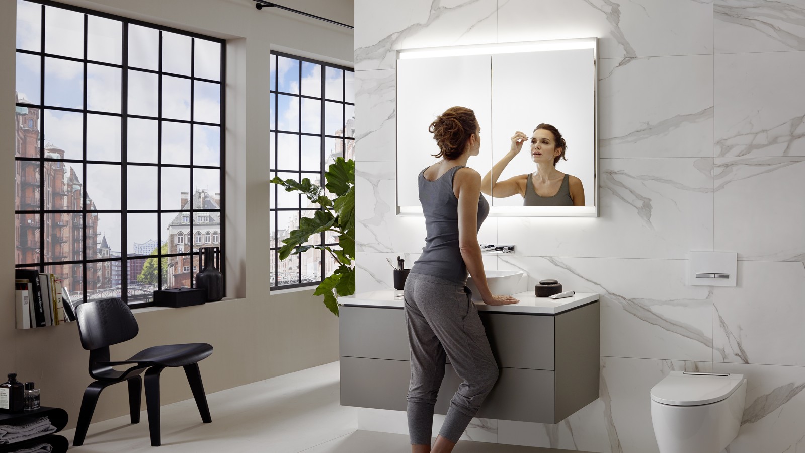 Woman standing in a Geberit ONE bathroom, with the washbasin mounted at the perfect height.