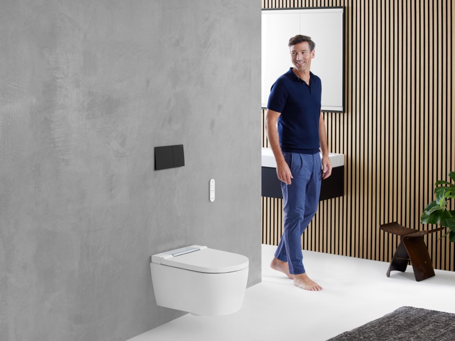 Man in bathroom with a wall-hung Geberit AquaClean Sela shower toilet Man in bathroom with a wall-hung Geberit AquaClean Sela shower toilet