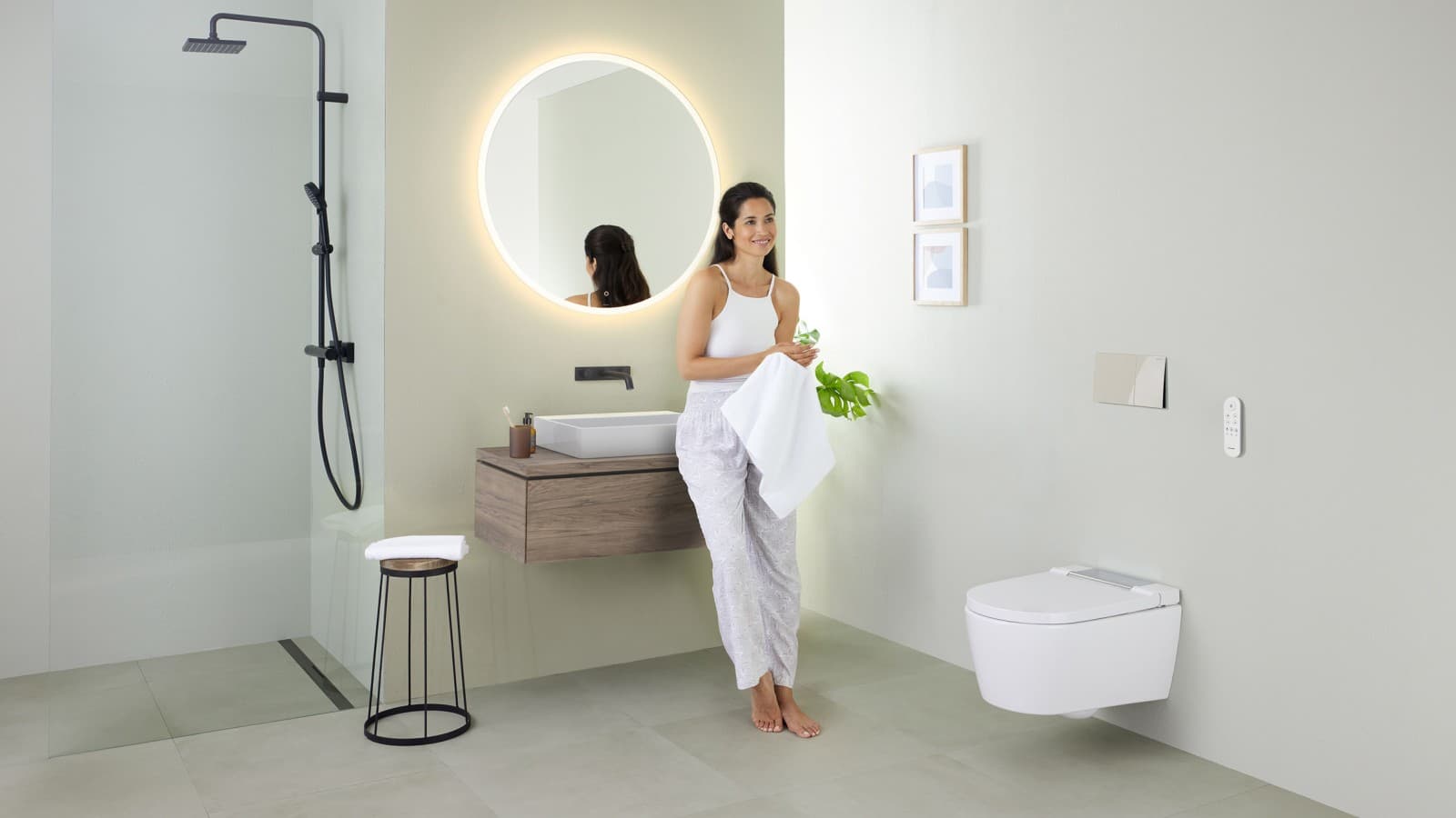Woman leaning on a washbasin in a bathroom with Geberit AquaClean Sela shower toilet Woman leaning on a washbasin in a bathroom with Geberit AquaClean Sela shower toilet