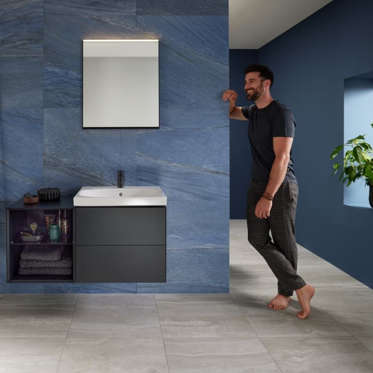 Man leaning against wall in blue bathroom with Geberit Mix & Match washplace Man leaning against wall in blue bathroom with Geberit Mix & Match washplace